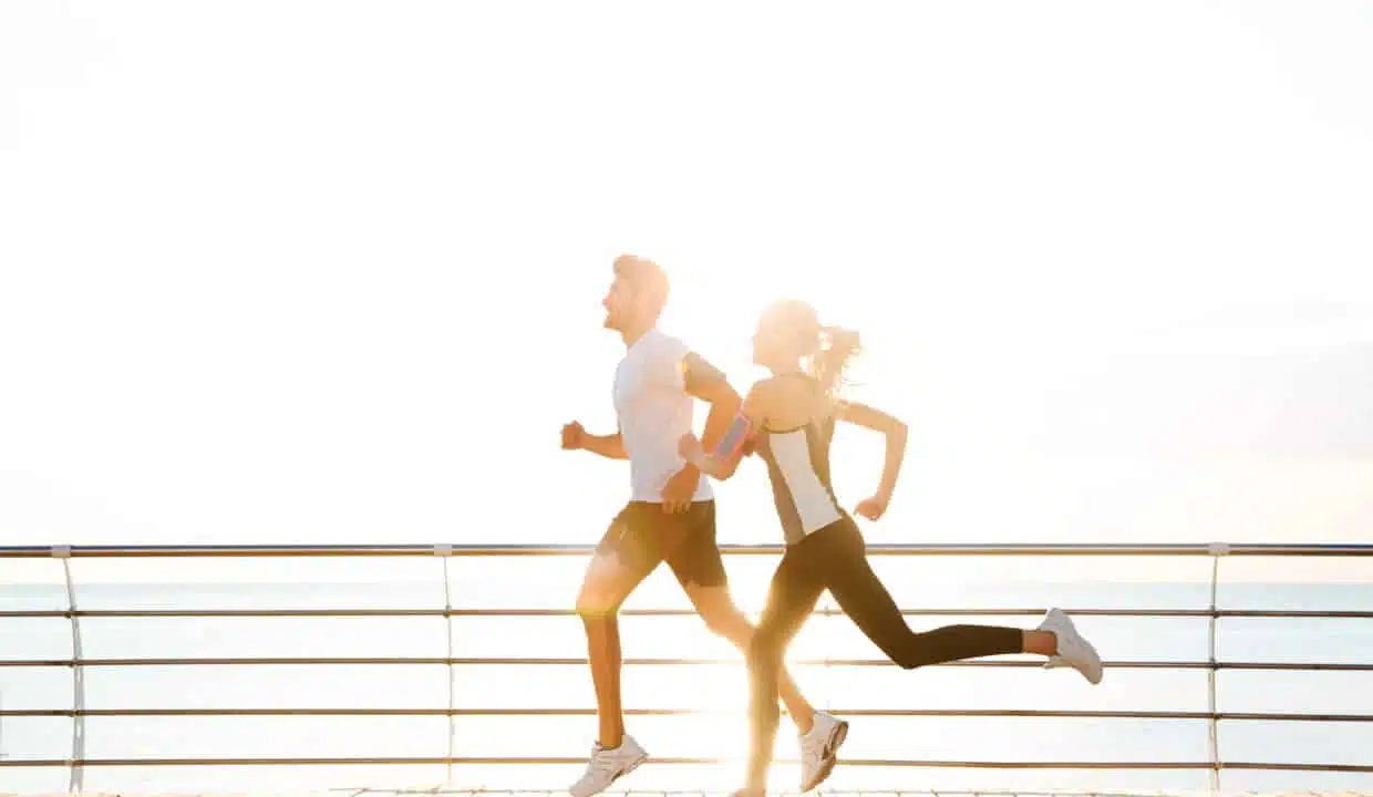 Young,Sporty,Couple,Running,Over,Wooden,Pier,At,Sunset